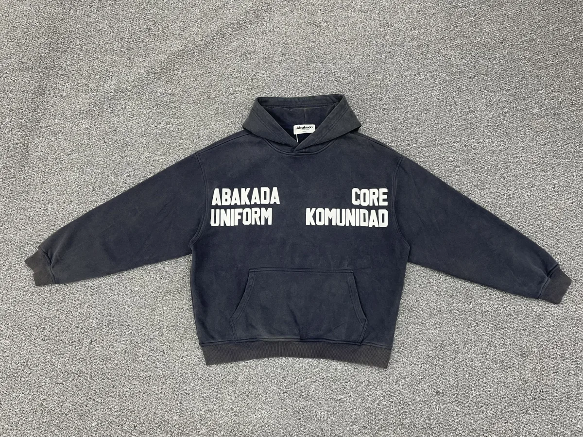 Navy hoodie with white chest lettering photographed flat on a textured surface