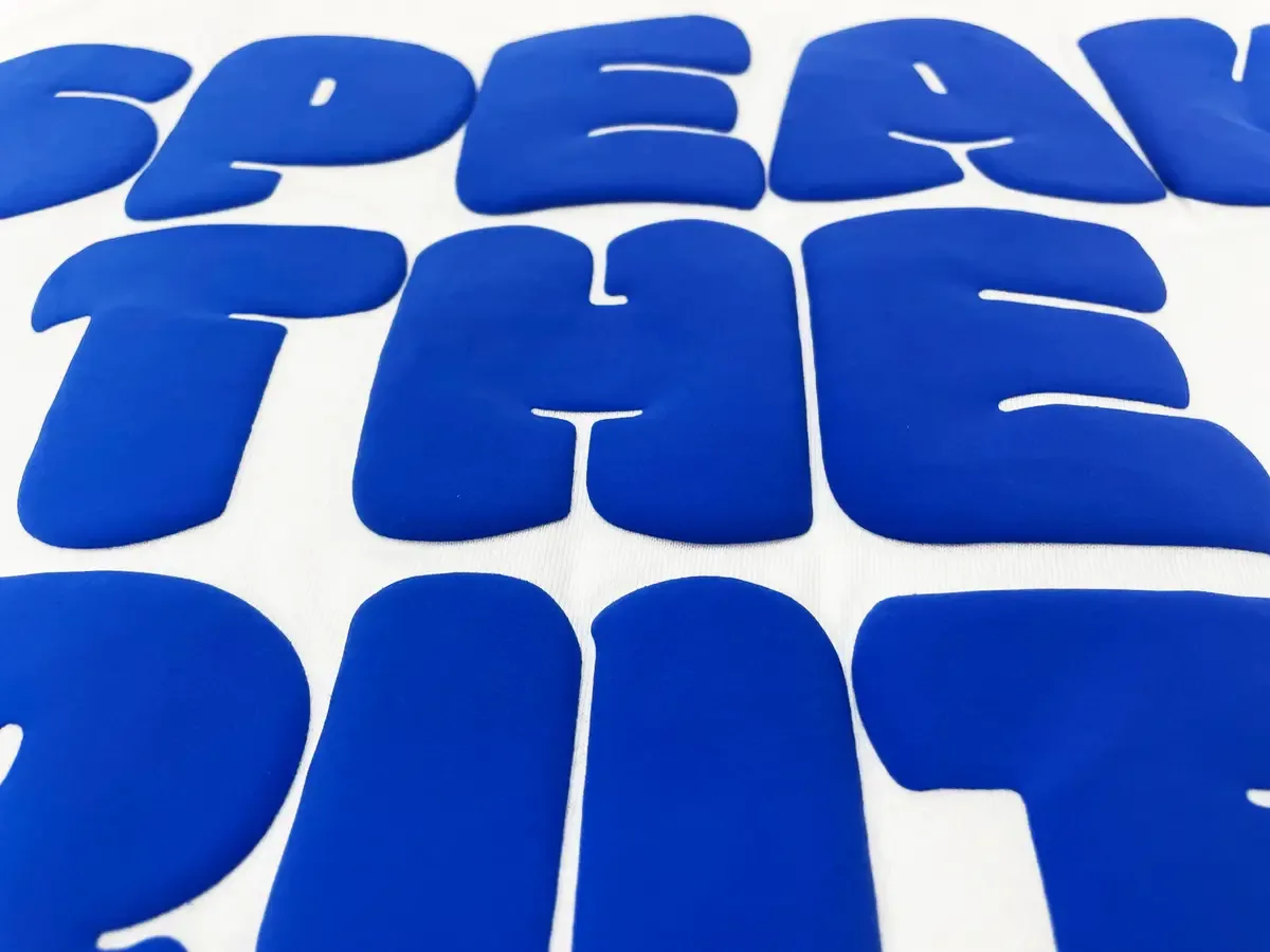 Raised blue printed lettering viewed at an angle on white fabric