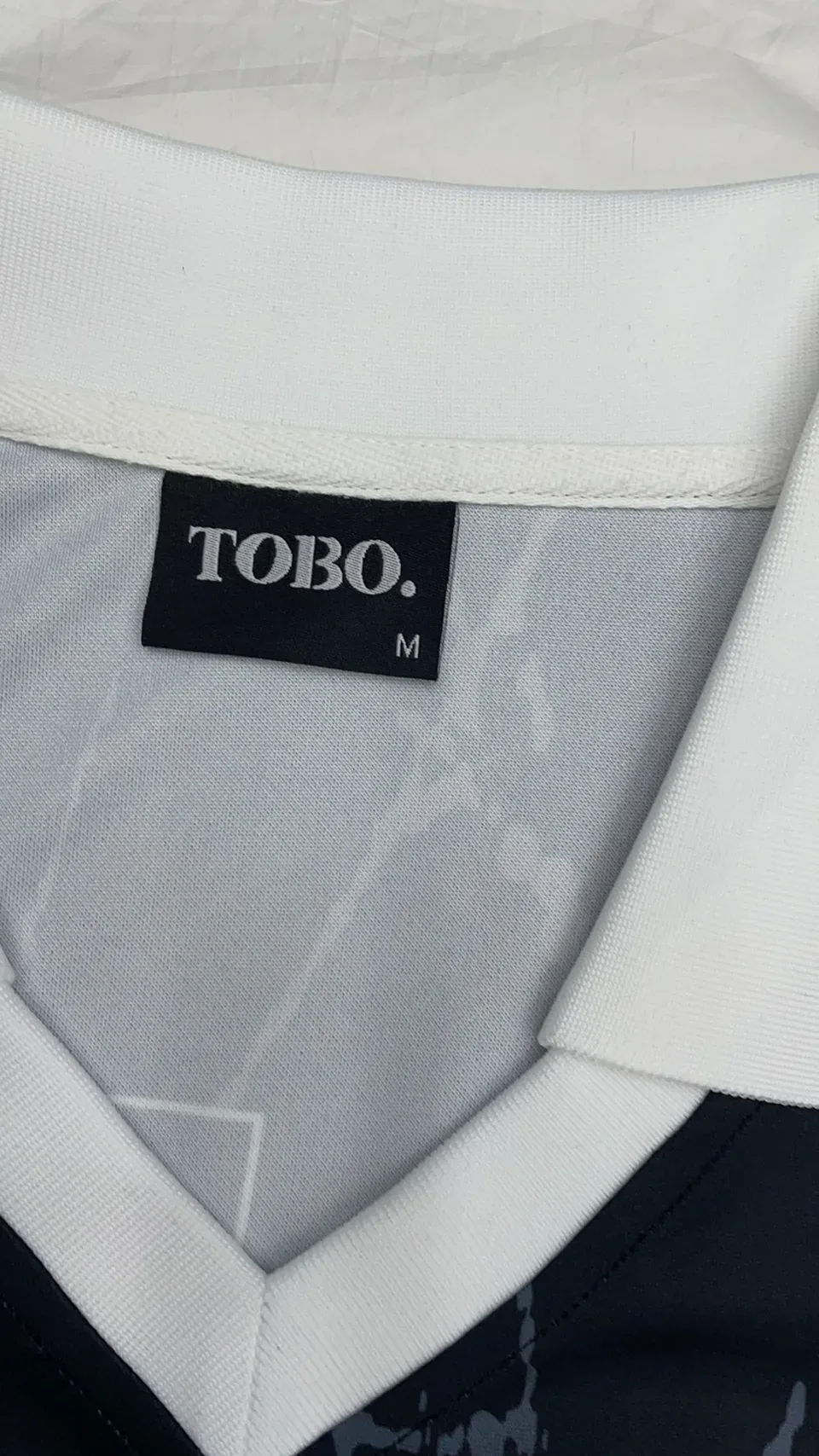 Black woven neck label sewn into a white garment neckline