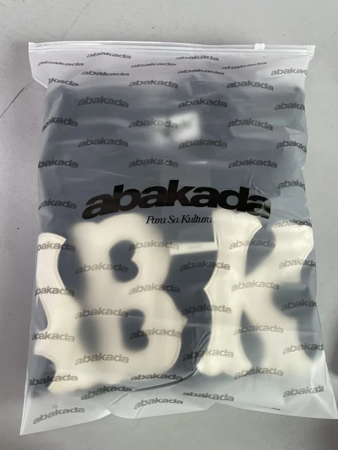 A garment packed in a translucent bag printed with Abakada branding