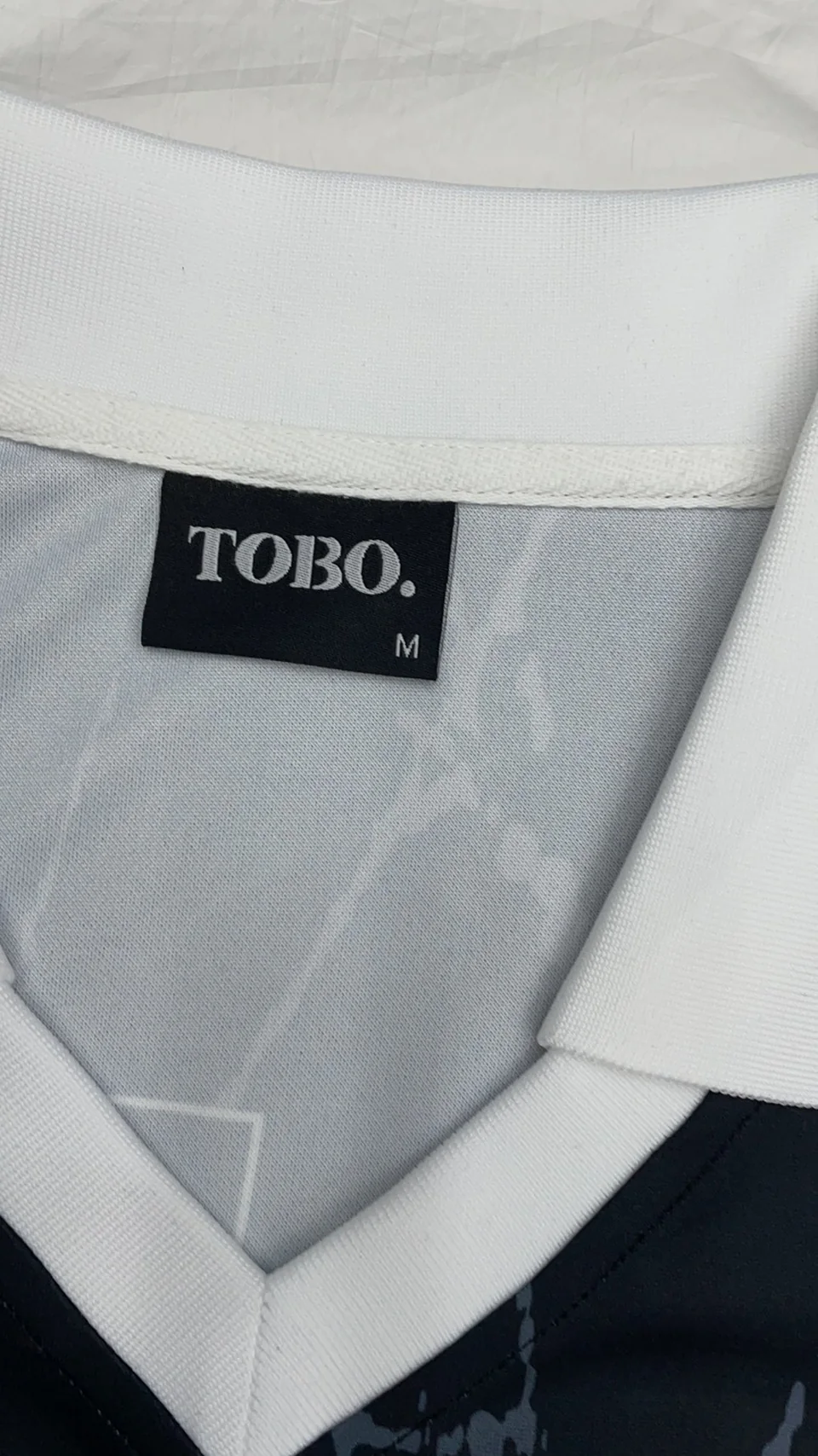 Black woven neck label sewn into a white garment neckline